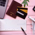 mise en place chèques vacances, carnet de chèques posé sur une table rose à coté d'un passeport
