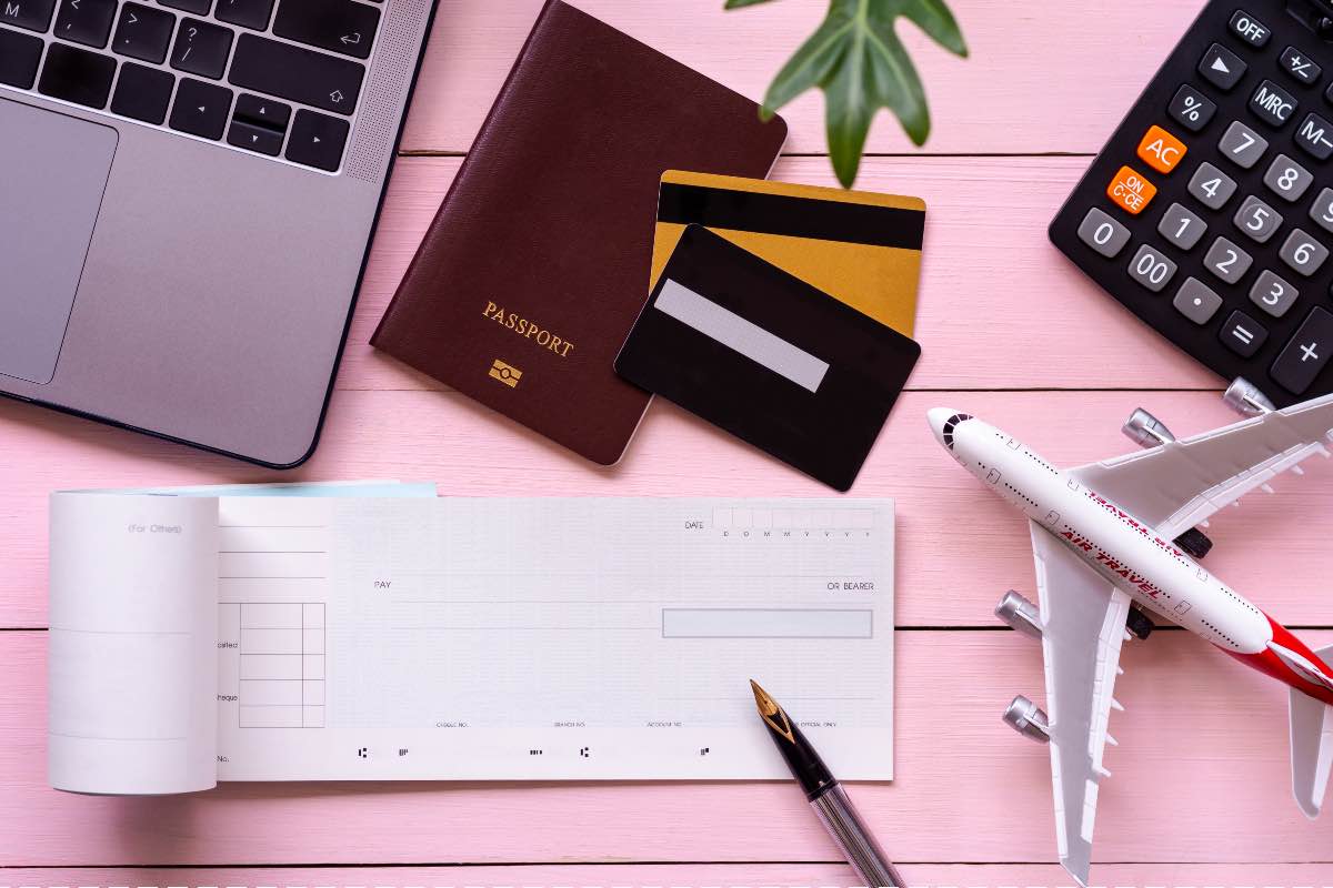 mise en place chèques vacances, carnet de chèques posé sur une table rose à coté d'un passeport