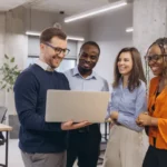 Groupe de professionnels engagés et heureux travaillant sur un ordinateur portable